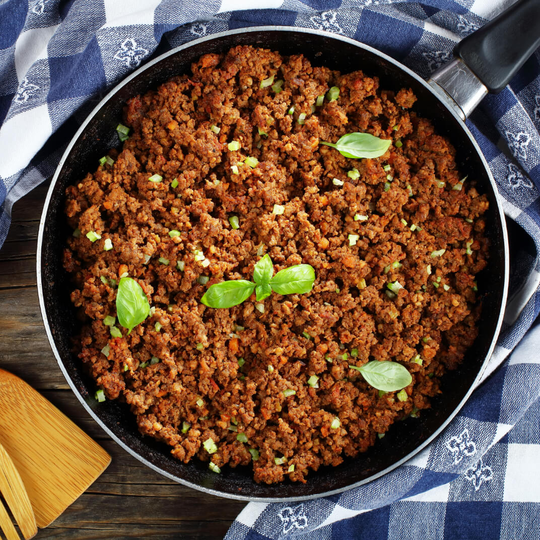 Photo of ground beef frying in pan with Basil.