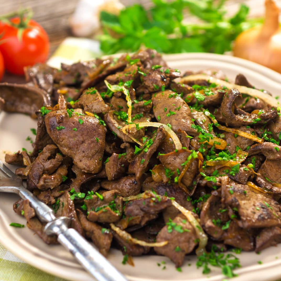 Photo of sautéed beef with caramelized onions, garnished with parsley.